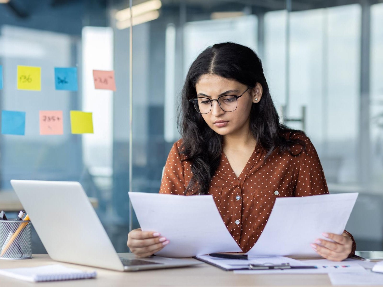 Focused businesswoman reviewing documents at a modern office desk
