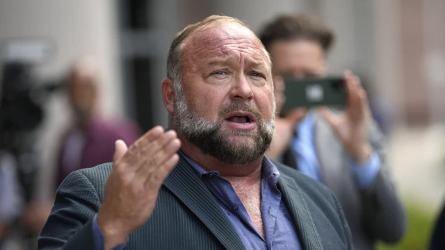 Alex Jones speaks to the media after arriving at the federal courthouse for a hearing in front of a bankruptcy judge.