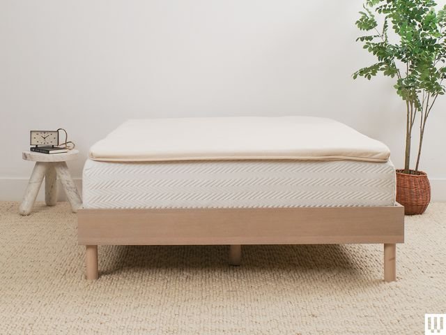 Birch Plush Organic Mattress Topper a beige pad on top of a white mattress resting on a minimalist wooden bedframe with...