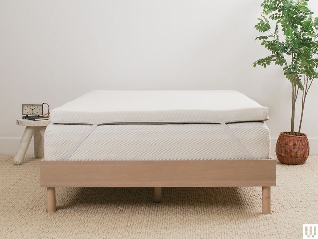 Helix Sleep GlacioTex Premium Mattress Topper a thick pad laying on top of a white mattress sitting on a light brown...