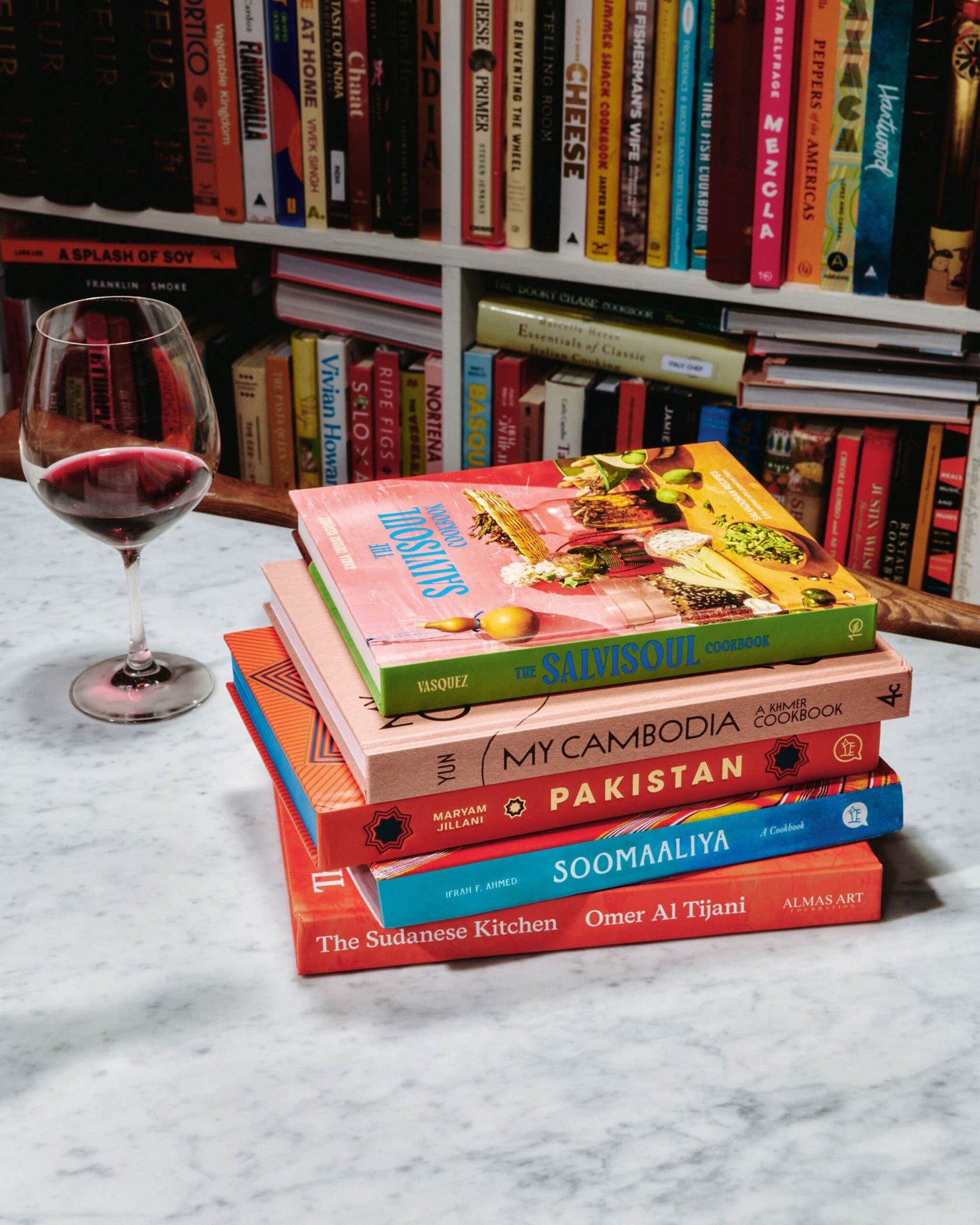 5 Must-Read Cookbooks That Champion Underrepresented Cuisines A stack of cookbooks arranged on top of each other, including My Cambodia, Pakistan, SalviSoul, The Sudanese Kitchen, and Soomaaliya.