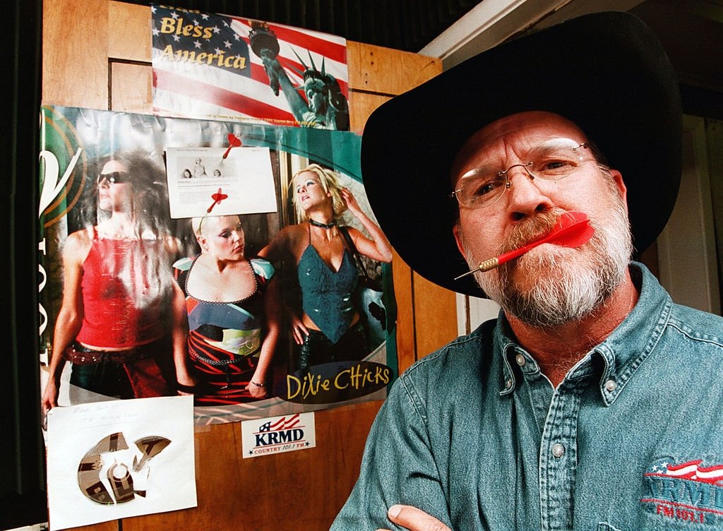 Shreveport, Louisiana, country radio personality K. C. Daniels stands in front of a poster of The Chicks he turned into a dartboard in March 2003 after lead singer Natalie Maines' comments against President George W. Bush.