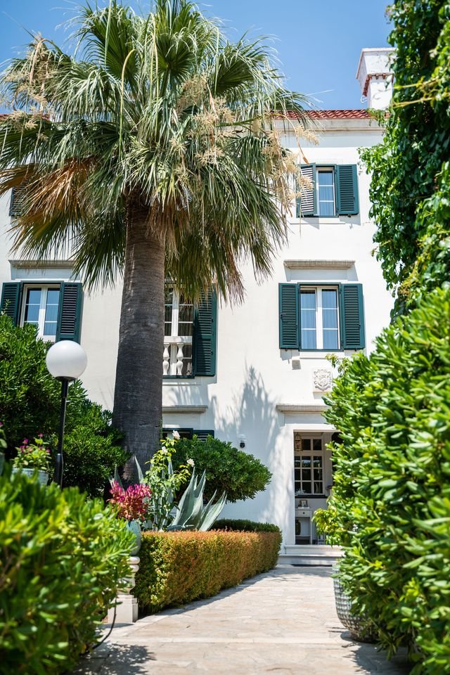 Image may contain Architecture Building House Housing Villa Plant Tree City Palm Tree Vegetation Urban and Fence
