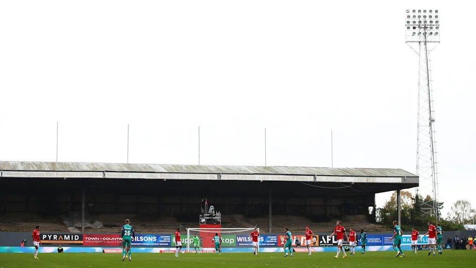 A wide lens picture of the disused Kop at Wrexham's Racecourse Ground during a game, prior to its demolition.