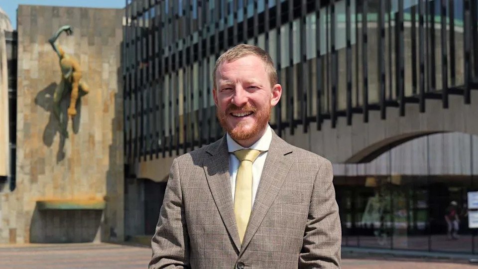 Newcastle City Council's Liberal Democrat leader Colin Ferguson, a man with fair hair and a beard, is smiling at the camera. He is wearing a light coloured suit jacket, white shirt and pale yellow tie.