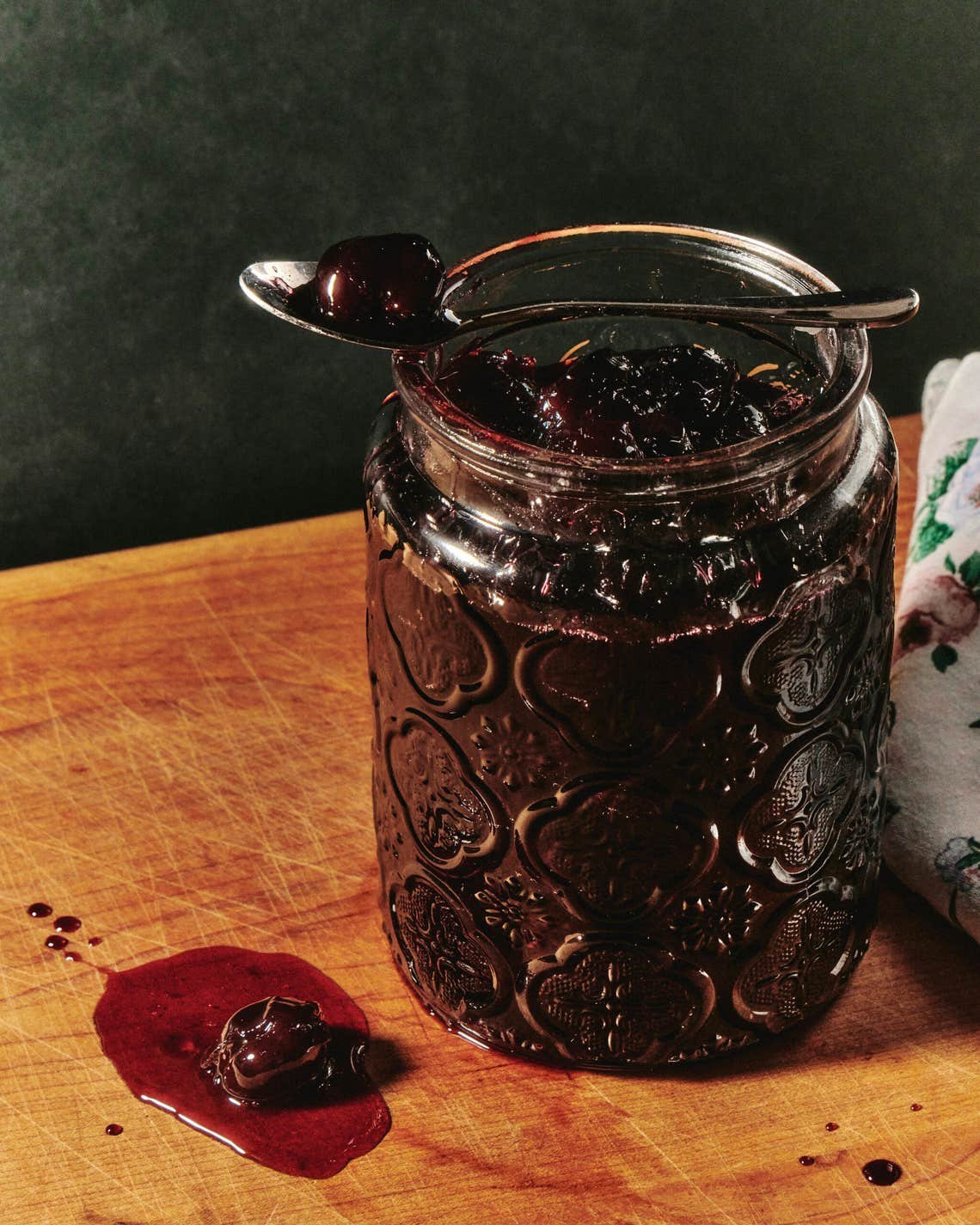 An open jar of Muraba Albalu (sour cherry preserve) with a spoon resting horizontally across the top of the jar. An open jar of Muraba Albalu (sour cherry preserve) with a spoon resting horizontally across the top of the jar.