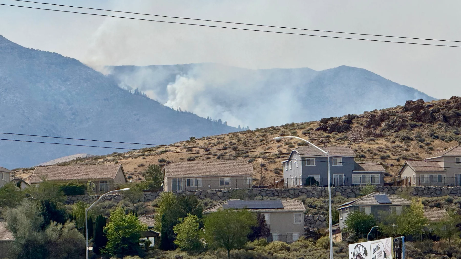 Smoke billows in the distance as a wildfire burns in Reno, Nev., Sunday, August 23, 2026. (AP Photo/Haven Daley)