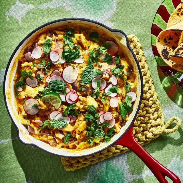 Masala scrambled eggs topped with sliced radishes and mint served in a skillet accompanied by a side of tortillas.
