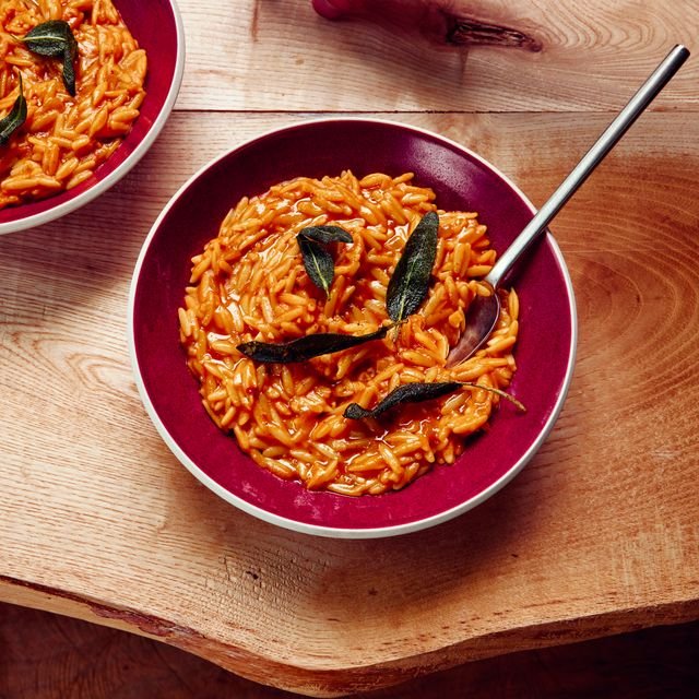 Cooked butternut squash with orzo and sage in red bowls