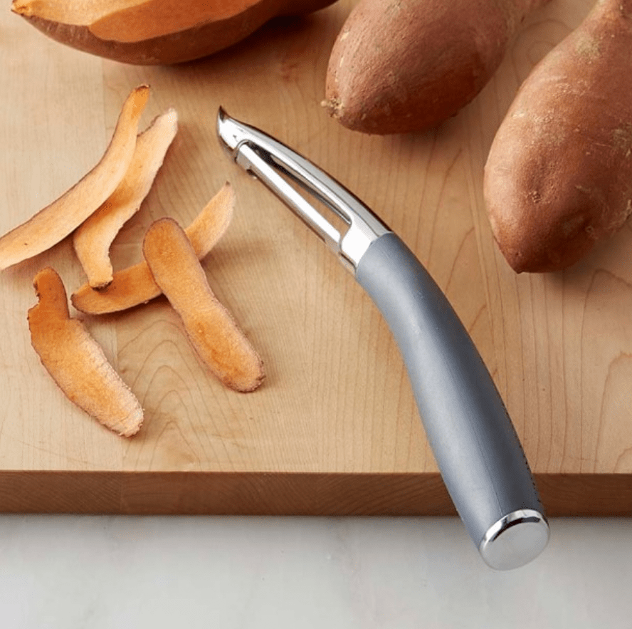 metal vegetable peeler with skin of sweet potato.