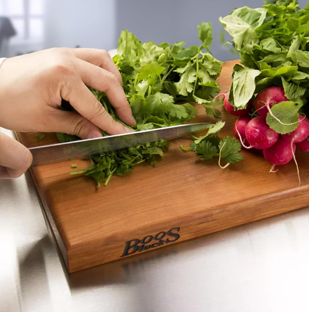 hand cutting radishes on a cutting board.