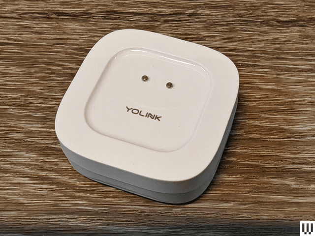 White rounded square device on wooden surface with brand name YoLink