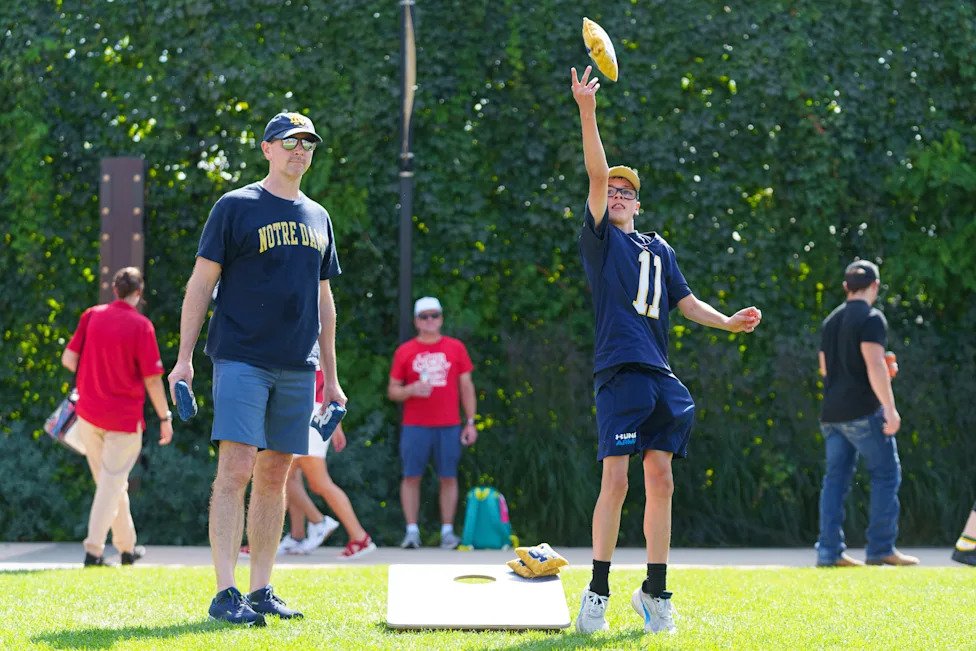 Andy Warnement, left, throws bags with his 12-year-old son Ben before a NCAA football game between Notre Dame and Wisconsin a