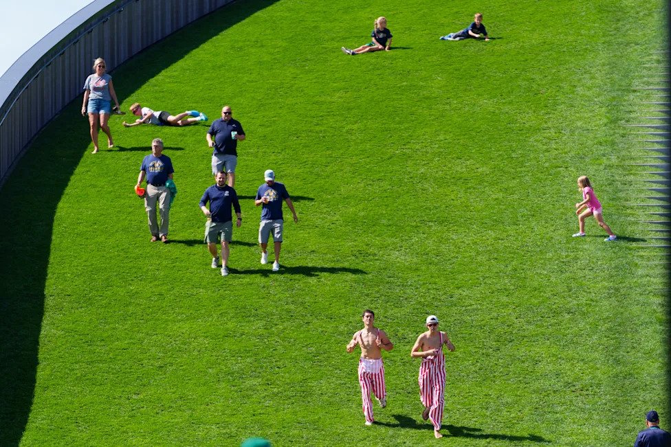 Fans run down a hill outside Lambeau Field before a NCAA football game between Notre Dame and Wisconsin on Sunday, Sept. 6, 2