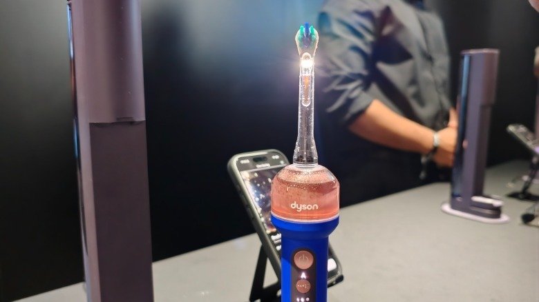 Dyson's CameraJet propped up in front of an iPhone showing the camera livefeed.