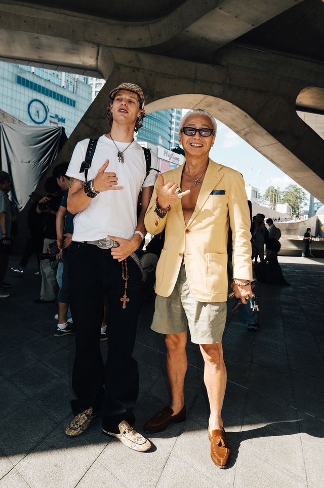 Image may contain Adult Person Clothing Shorts Blazer Coat Jacket Body Part Hand Finger Photobombing and Face