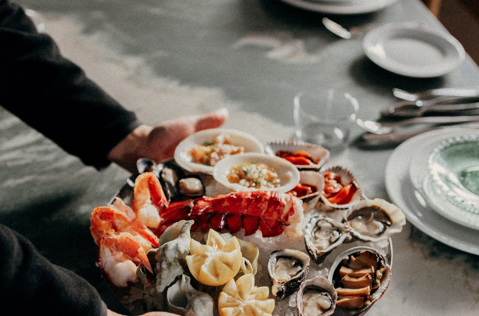 A platter of seafood on ice, including a big lobster tail, oysters, shrimp, and others.