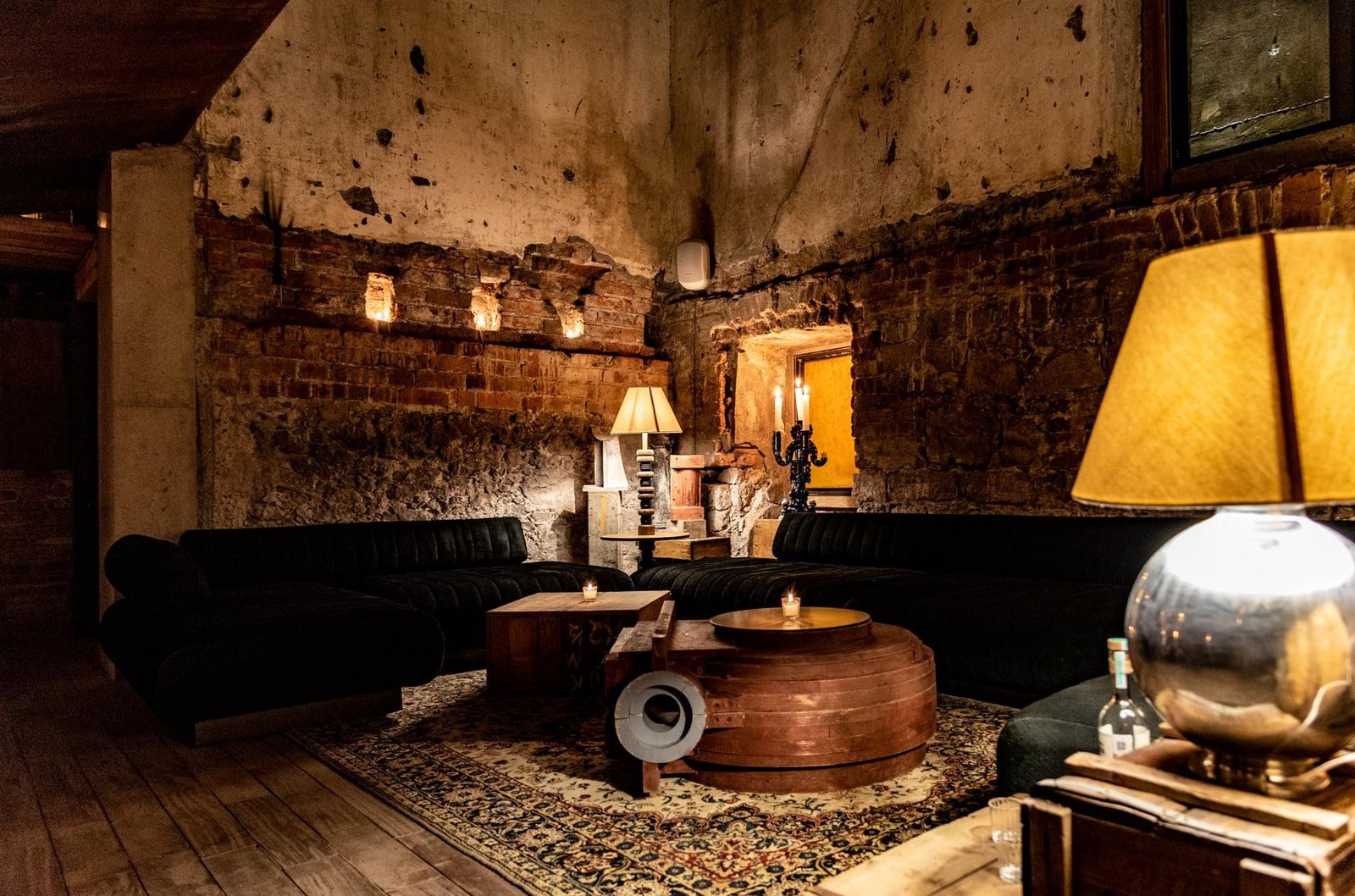 A seating area with exposed brick walls, candles, and low couches.