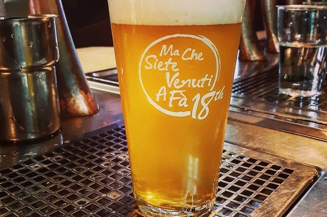 A branded pint glass full of beer on a bar.