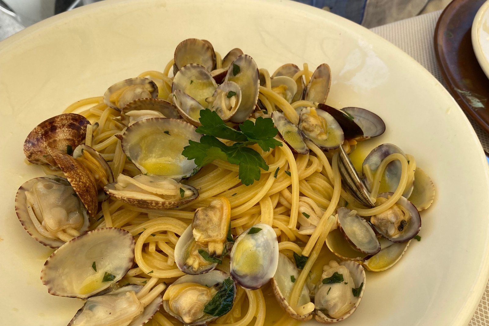 Spaghetti with clams in a shallow plate with a diner sitting behind.