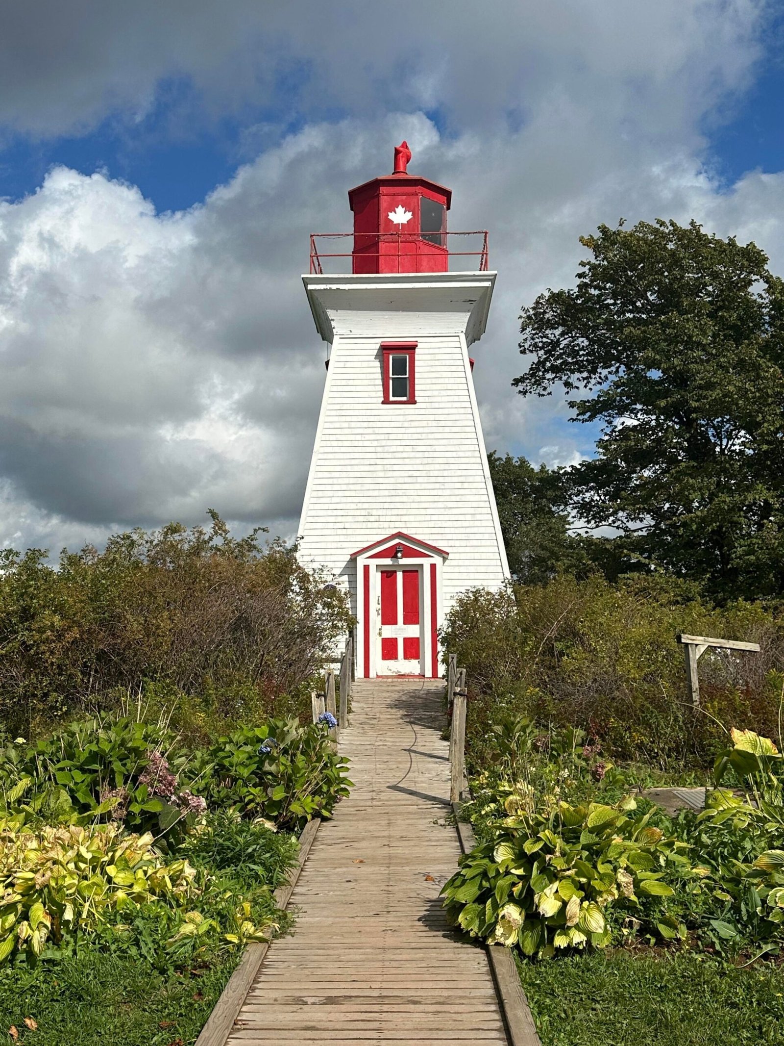 A white clapboard lighthouse with blue sky in the background.