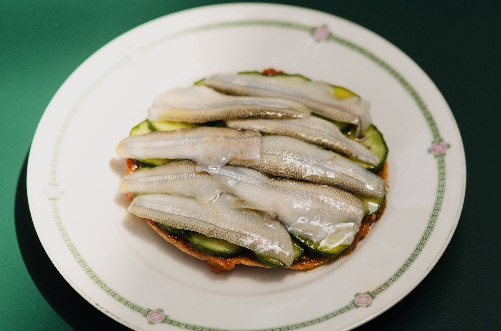 Slices of fish on an avocado-covered tostada.